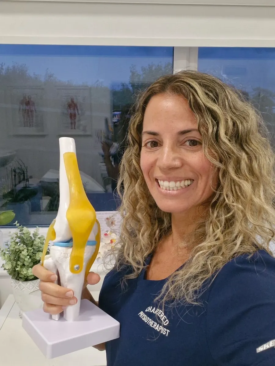 Irina Parreira, Chartered Physiotherapist, holding a model of a knee joint